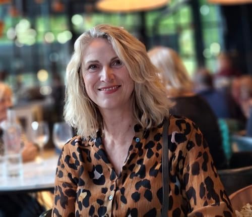 Woman with blonde hair smiling, wearing a leopard-print shirt.