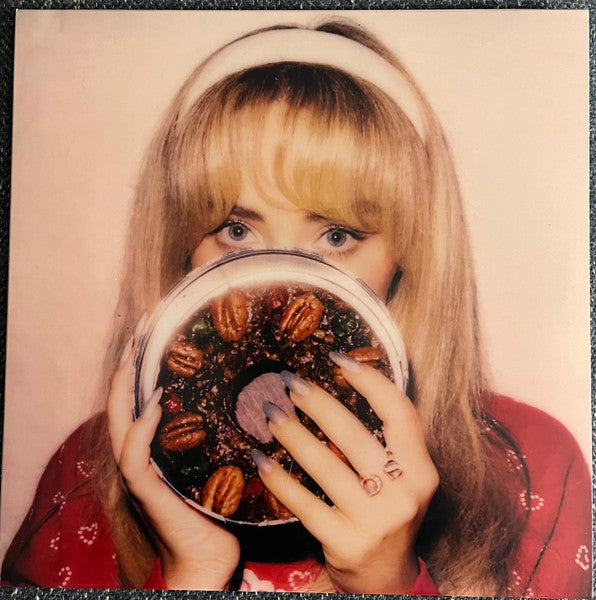 Woman with blonde hair holding a fruitcake up to her face.