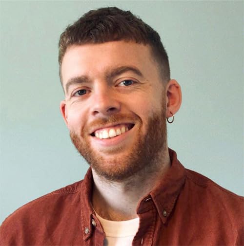 A smiling man with a short haircut, beard, and hoop earring wearing a shirt.