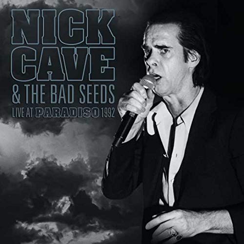 Black and white portrait of Nick Cave singing into a microphone.