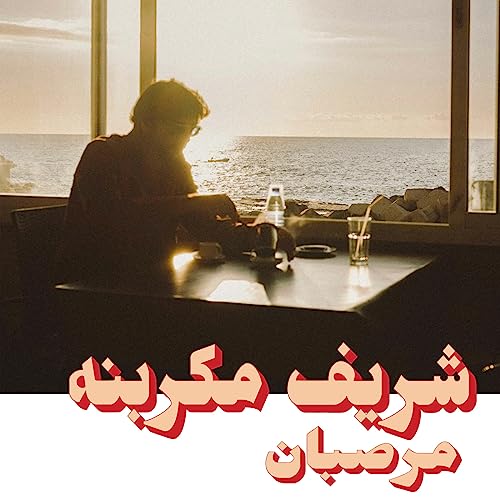 Man at table by window overlooking ocean, album cover art.
