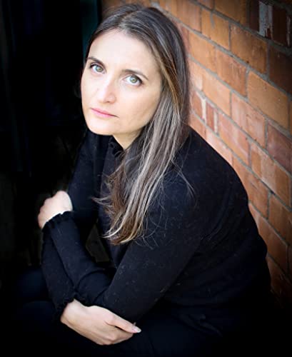 Portrait of author Claire Contreras, leaning against a brick wall.