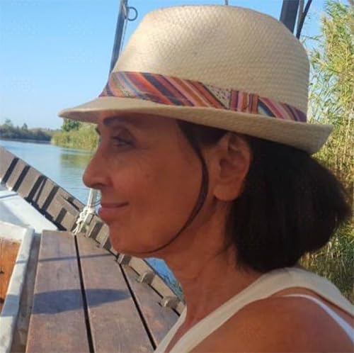 Woman in a straw hat with striped ribbon, looking towards water.