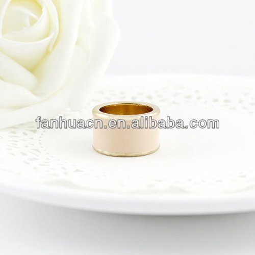 Pink and gold metal ring on a white, patterned surface.