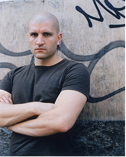 Bald man with an earring and crossed arms, facing forward.