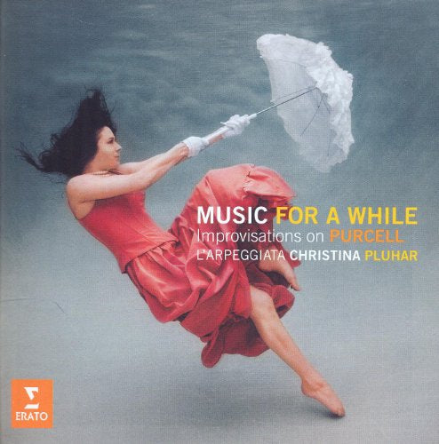 Woman in red dress leaps with parasol against blurred blue background.