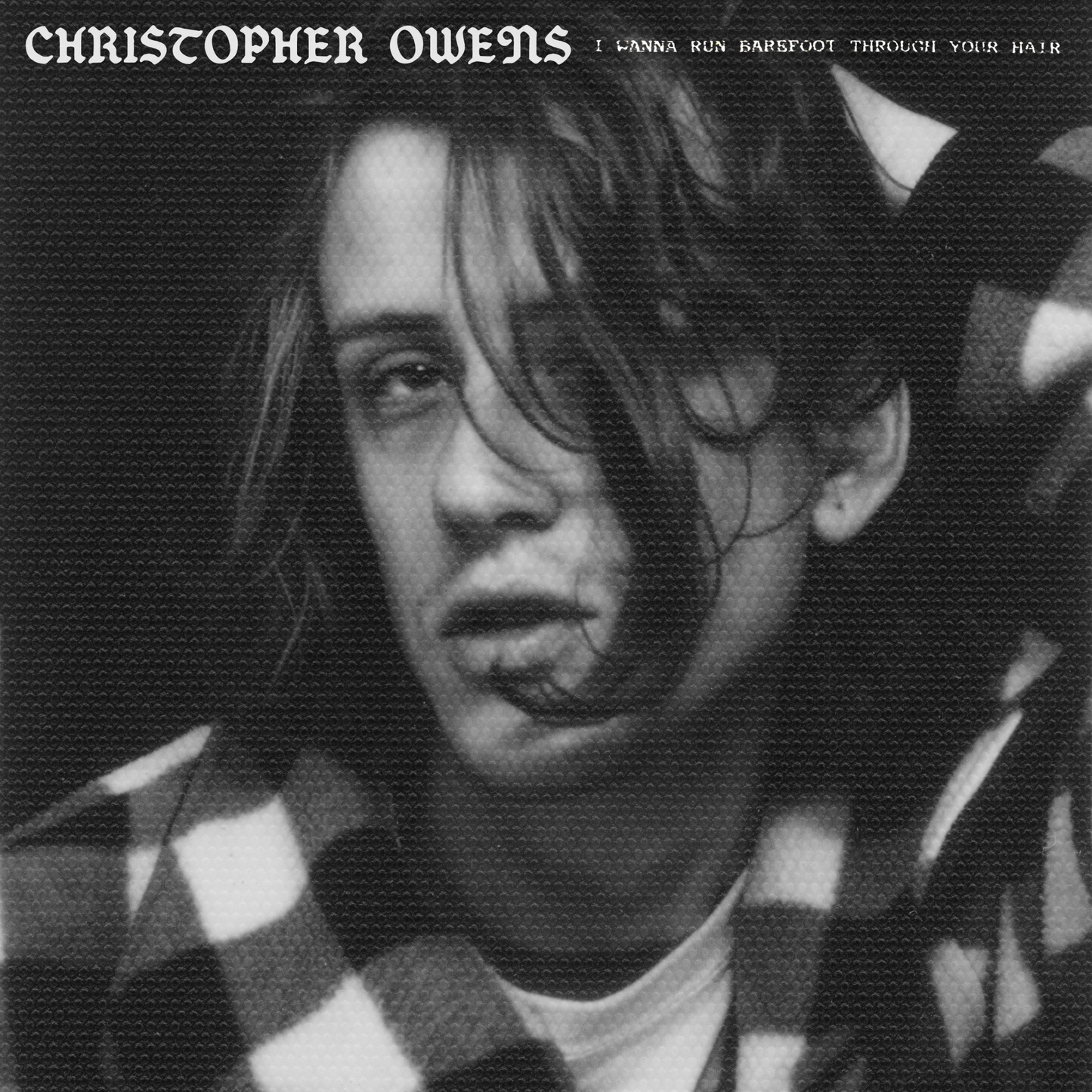 Black and white portrait of musician Christopher Owens with plaid background.