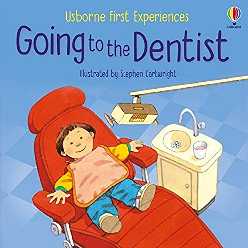 A young child reclines in a red dentist's chair wearing a pink bib.