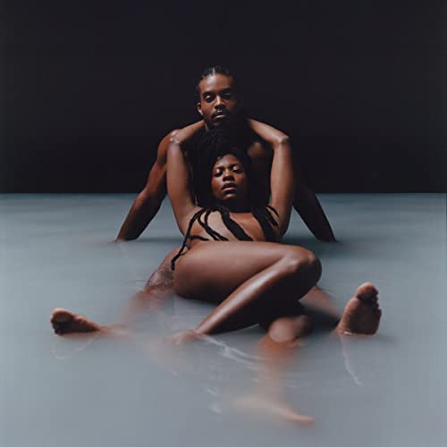 Two people embrace intimately in shallow, milky water.