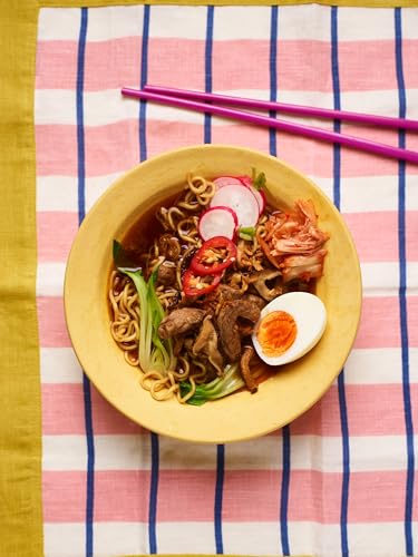Noodle bowl with meat, vegetables, egg, and pink and purple chopsticks.