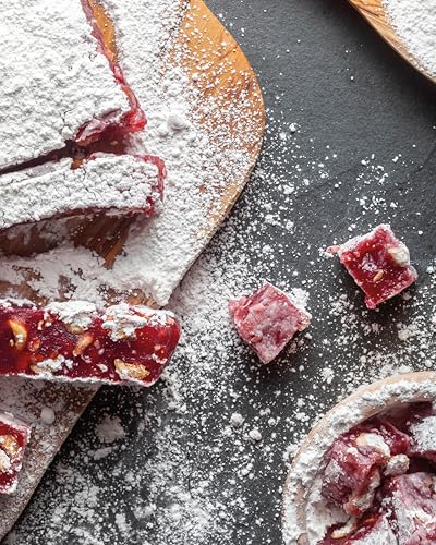 Red rose petal jelly squares dusted with powdered sugar on a wood board.