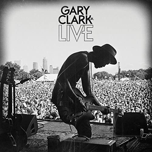 Gary Clark Jr. playing guitar onstage before a large crowd.