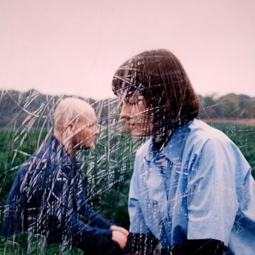 Two people with obscured faces in a grassy field.