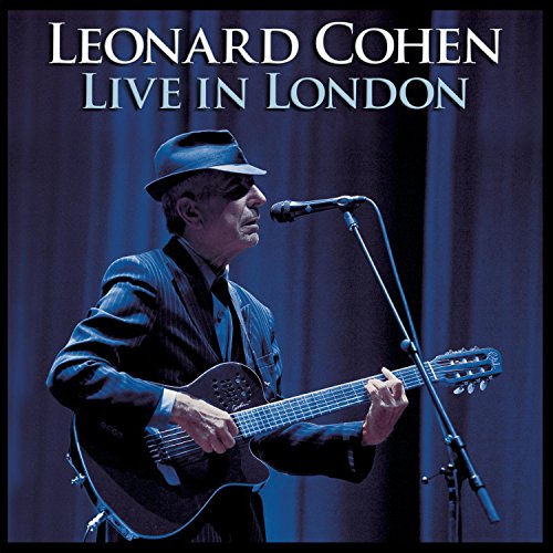 Leonard Cohen wearing a fedora and suit, playing guitar on stage in blue light.