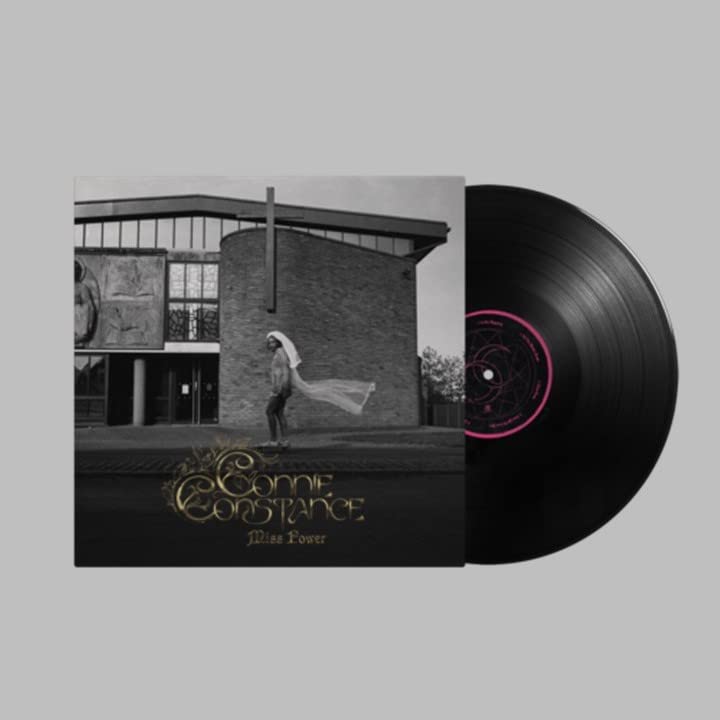 Vinyl record with album cover featuring a woman in white near a building.