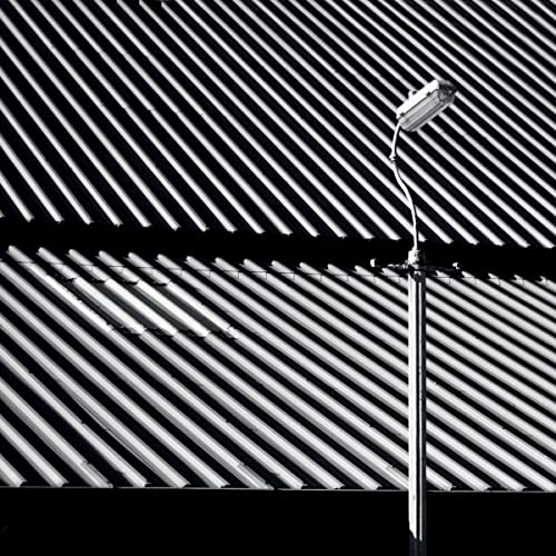 A street lamp stands against a background of diagonal corrugated metal siding.