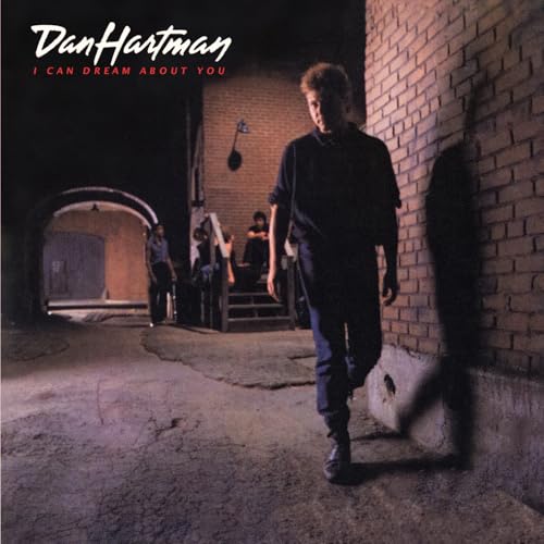 Dan Hartman walks along a brick wall in a dimly lit, urban alleyway.
