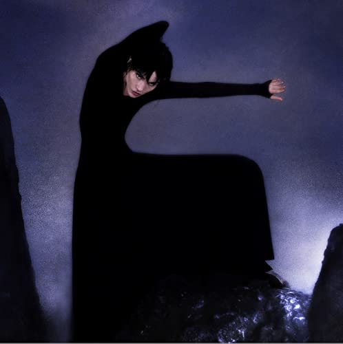 Dark portrait of a person in black clothing, dramatically posed.