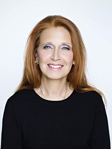 Headshot of a smiling woman with long red hair and a black top.