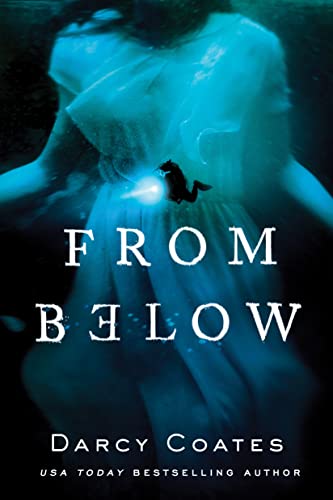 A diver with a flashlight approaches a woman in a white dress underwater.