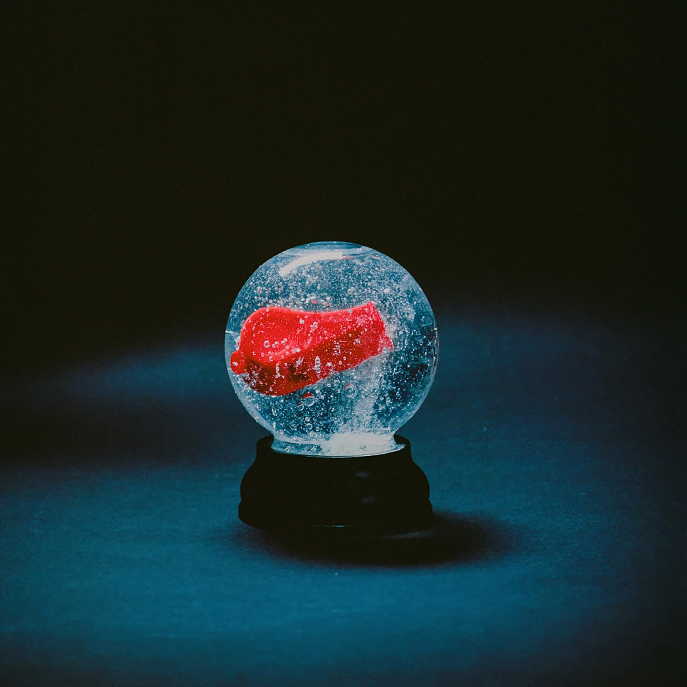 Snow globe containing a red, abstract shape against a dark background.