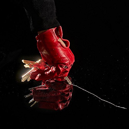 Red, gloved hand clutching keys against a dark, speckled background.