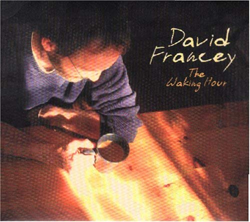 CD cover featuring a man looking through a magnifying glass at a lit surface.
