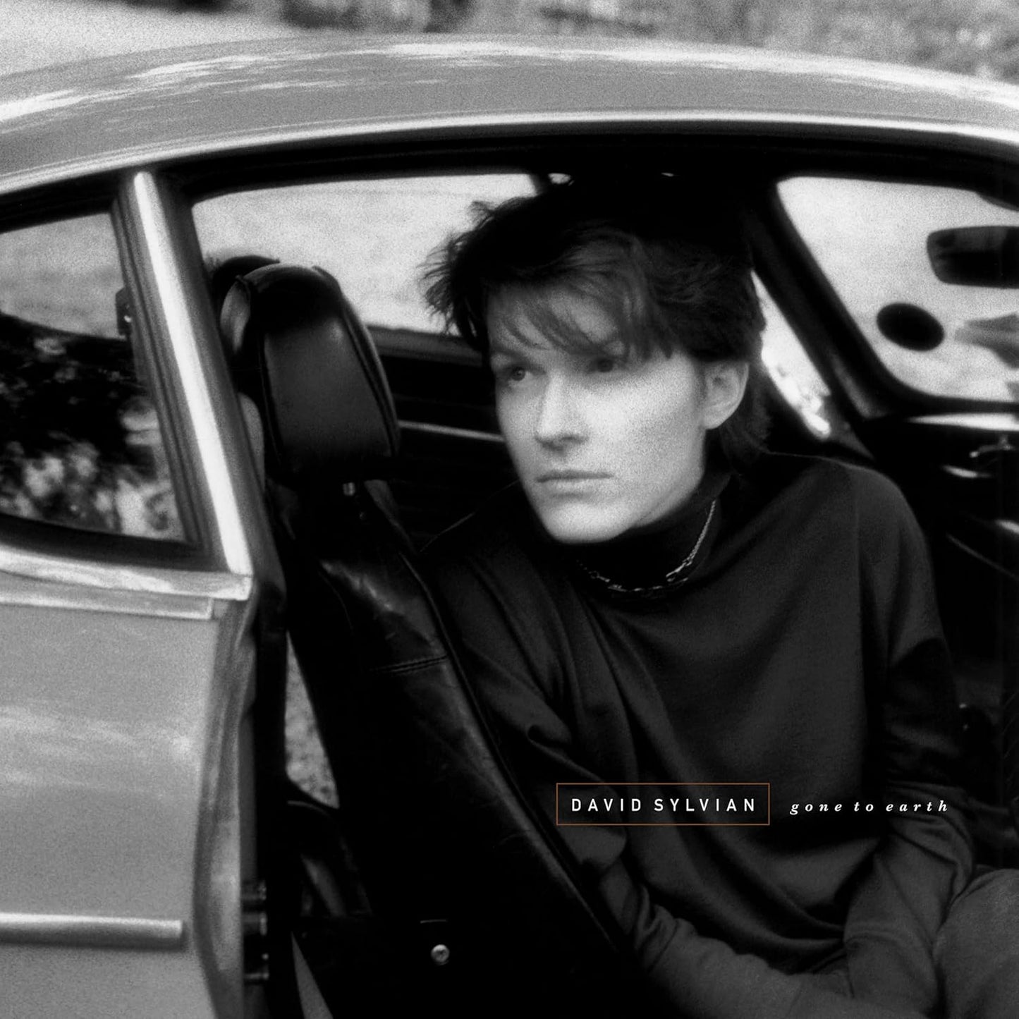 Black and white photo of David Sylvian sitting in a vintage car.
