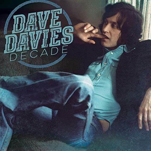 "Album cover featuring a man sitting on a couch, wearing a blue shirt and jeans."