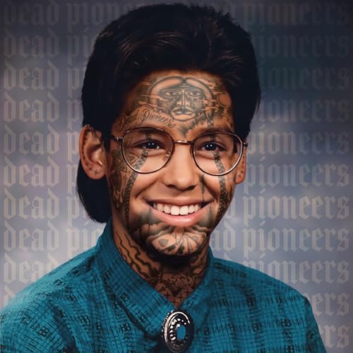 Portrait of a smiling person with extensive facial tattoos wearing glasses and a bolo tie.