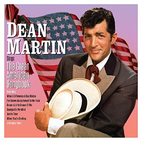 Dean Martin holding a straw hat in front of an American flag background.