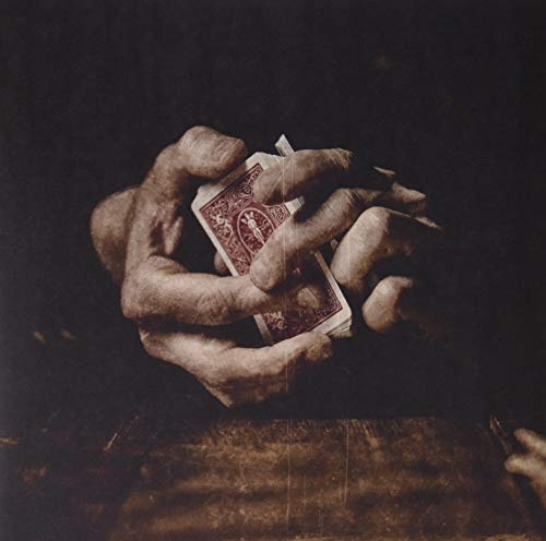 A pair of hands holding a deck of playing cards against a dark background.