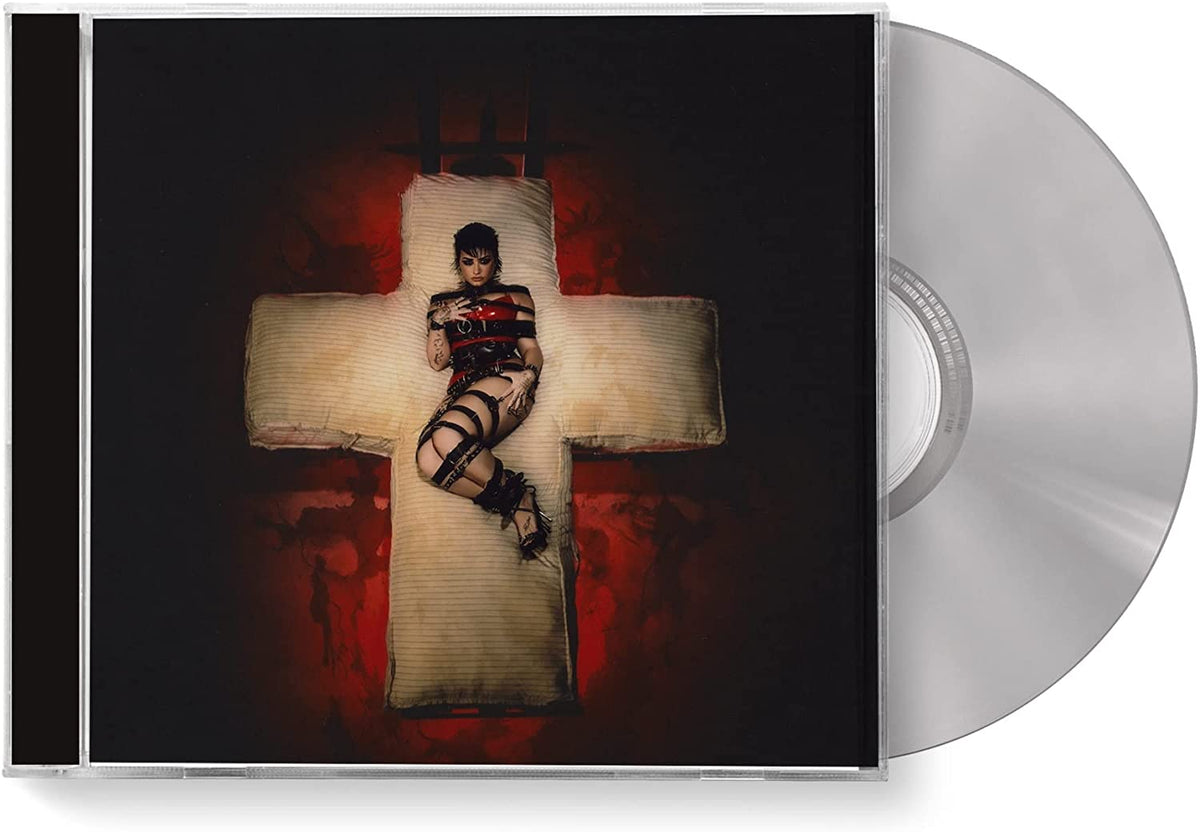 Demi Lovato lying on a cross, wearing red and black lingerie, against a dark red background.