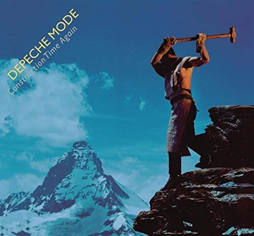 A shirtless man swings a sledgehammer against a rock with snowy mountains in background.