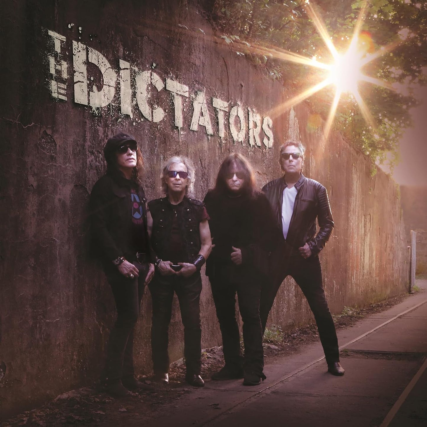 The Dictators band members stand in front of a graffiti-covered wall.