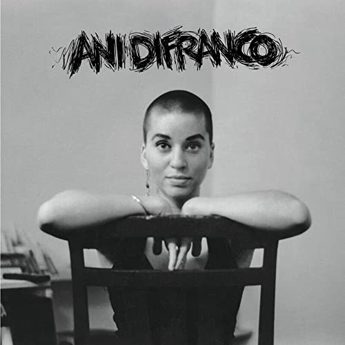 Black and white portrait of Ani DiFranco resting on chair arms.
