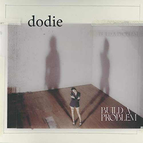 Album cover with a woman standing in a room, shadows on the wall behind her.