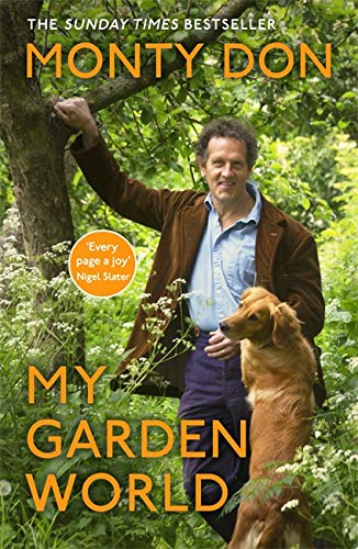 Monty Don standing in a lush garden next to a golden dog.