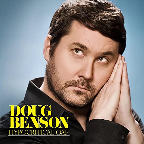 Doug Benson rests his head on his hands against a blue background.