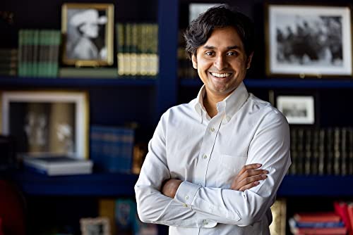 Man with dark hair and a white shirt, smiling at the camera.