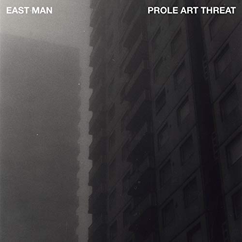 Dark album cover featuring a tall, grey concrete apartment building.