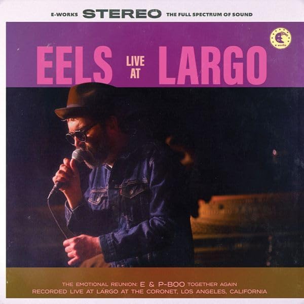 Eels album cover: a man with a hat sings into a microphone onstage.