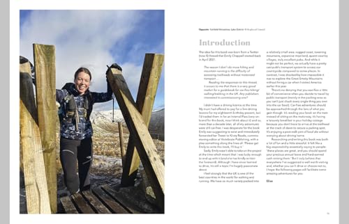 A smiling woman in hiking gear stands between wooden trail markers in a landscape.