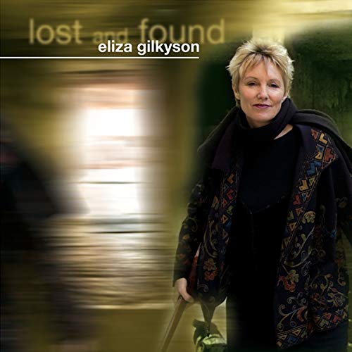 Eliza Gilkyson wearing a patterned jacket against a blurred background with album text overlay.