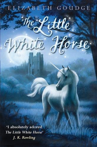 A white unicorn stands in a moonlit field before a castle at night.