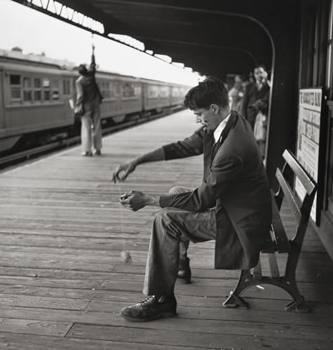Black and white photo of a man in a suit on a train platform.