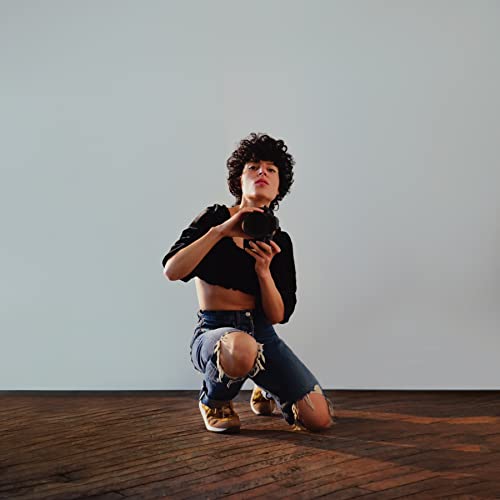 Emily King album cover: woman kneeling, holding a vintage camera.
