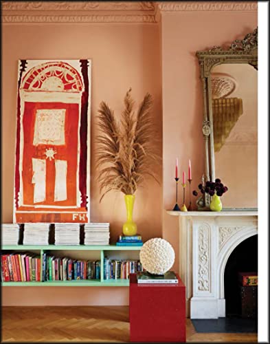 Peach-walled room with art, books, a mirror, and decorative objects.