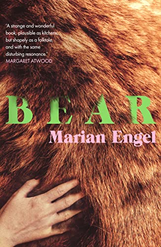 A human hand touches thick brown fur on the cover of the book Bear.