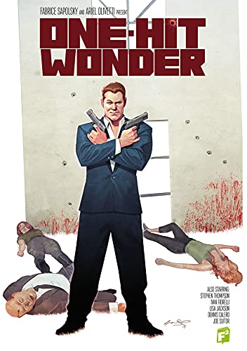 A man in a suit holds two guns with bodies lying on the ground.